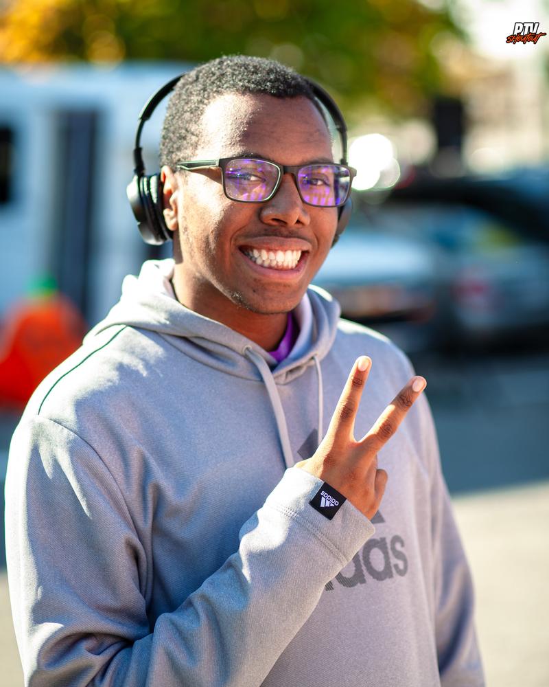Smiling OSL student in headphones giving a peace sign at the fall festival